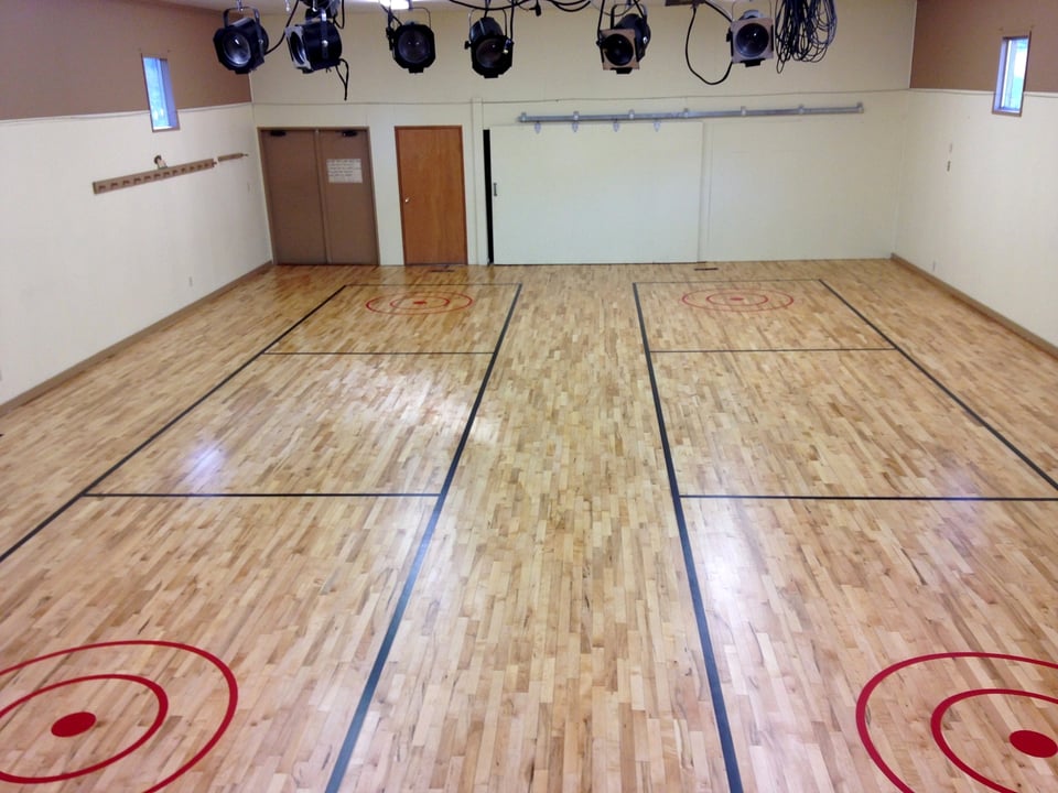 Sanded and finished gym floor with line markings for multiple courts