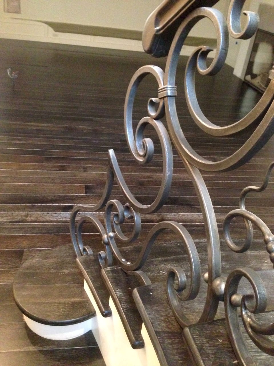 Sweeping wrought-iron staircase with hardwood treads seen from the entry